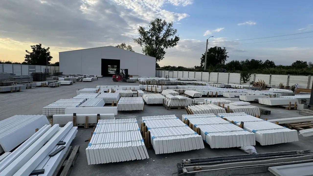 Der Werkshof in der Abenddämmerung: Paletten mit weißen Platten vor der Halle