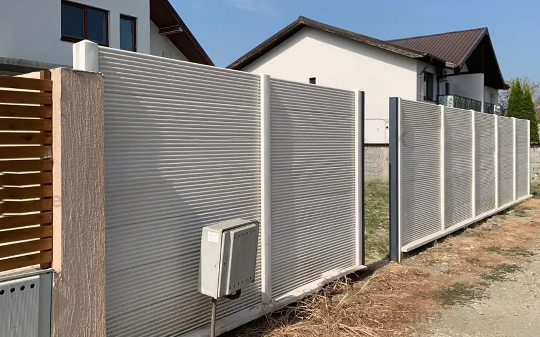 Betonzaun mit feinem horizontalem Relief vor einem Haus